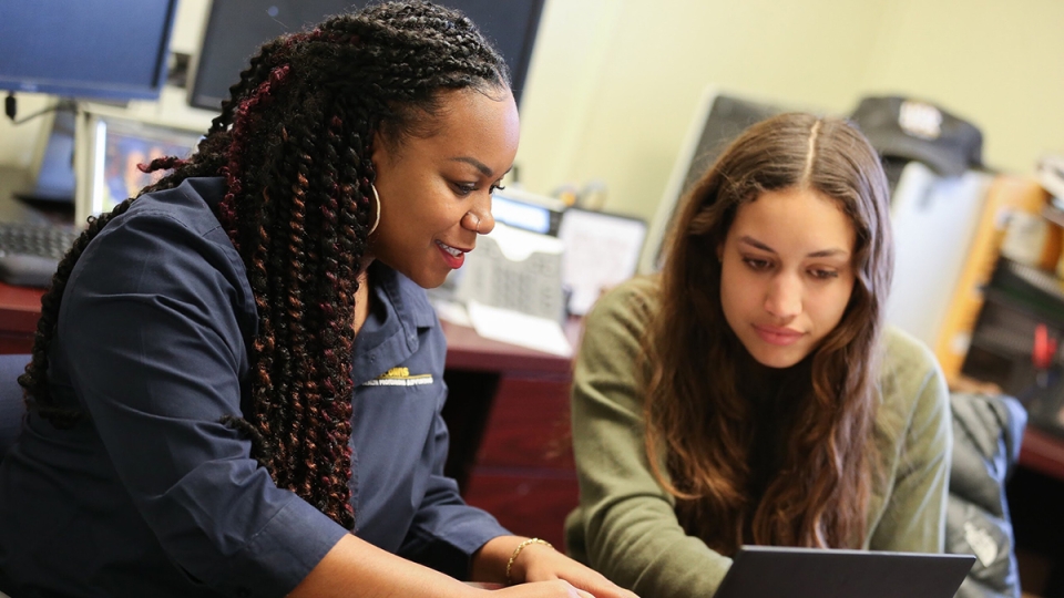 An advisor and a student looking at a laptop screen in an office.