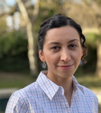 Somayeh Nassiri wearing a checkered button-down shirt in front of a blurry background with trees.