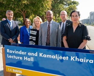 Campus leadership pose with donor couple Ravinder and Kamaljeet Khaira behind the lecture hall's building sign.